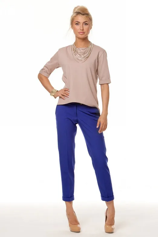 Девушка в блузке пастельных тонов и синих брюках.