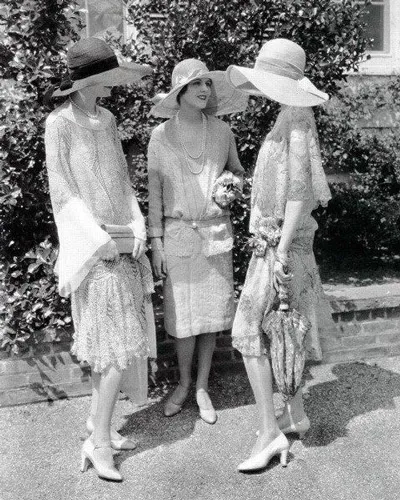 Три девушки в стиле Гэтсби в платьях с талией и широкополых шляпах.