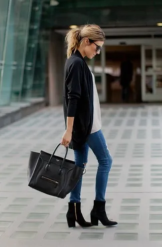 Девушка на улице с черным кардиганом, черной сумкой и синими джинсами.