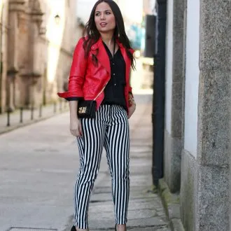 Черно-белые полосатые брюки с черной блузкой, туфлями и красным пиджаком.