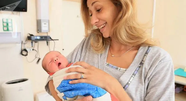 Женщина с новорожденным на руках в родильном доме