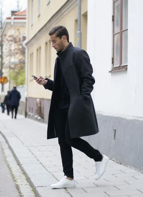Мужчина в белых туфлях и черном пальто