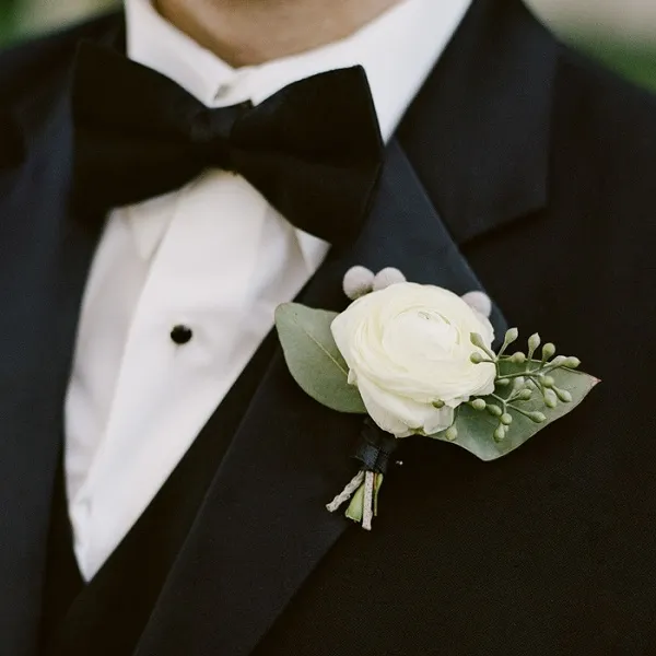 Белая бутоньерка на черном пиджаке жениха