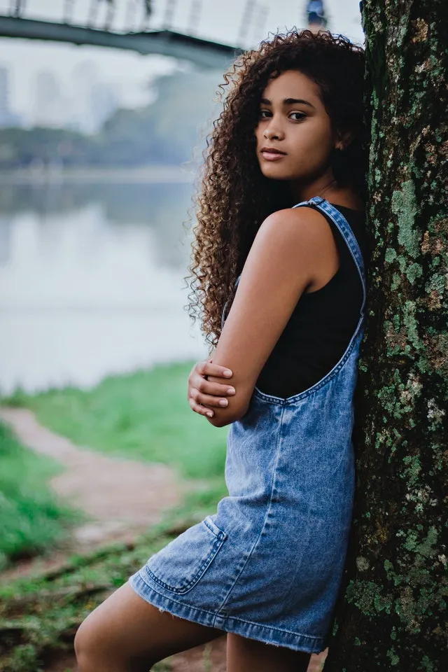 Девушка возле дерева в джинсовом сарафане