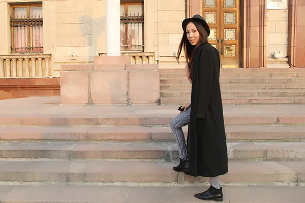 Девушка в черных туфлях и длинном черном пальто
