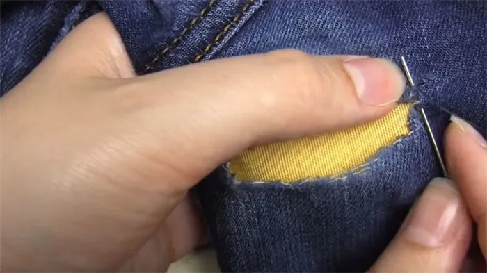 Сделайте первый стежок, чтобы зашить отверстие в джинсах.