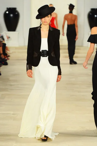 Модель в длинном белом платье и черном пиджаке.