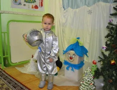 Серебряный костюм космонавта для ребенка возле новогодней елки