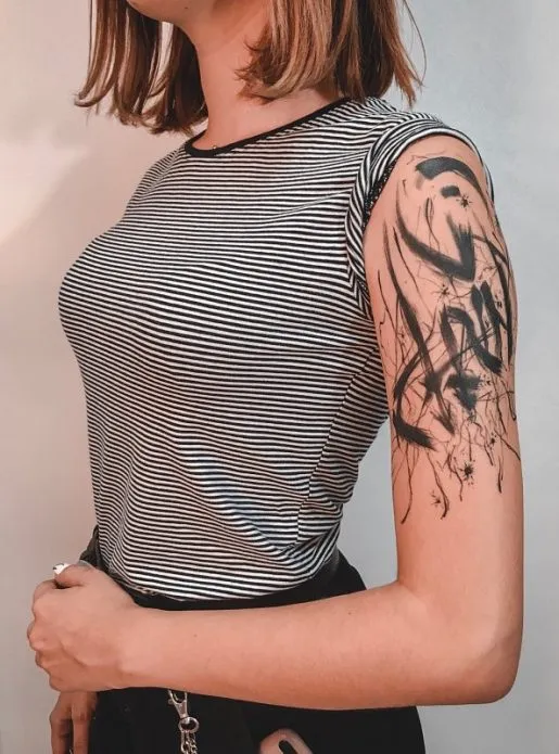 Черная акварельная татуировка на плече