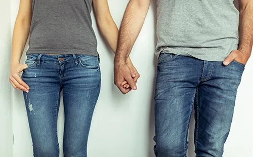 Парень и девушка в джинсах держатся за руки