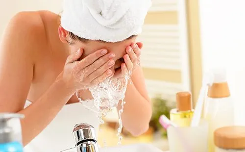 Женщина в ванной умывает лицо
