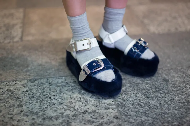 Серые носки сочетаются с сине-белыми сандалиями на высокой меховой подошве и с ремешками.