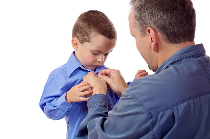 Папа помогает сыну застегнуть рубашку