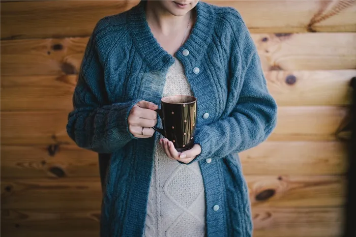 woman in a woolen sweater witn a cup of hot tea