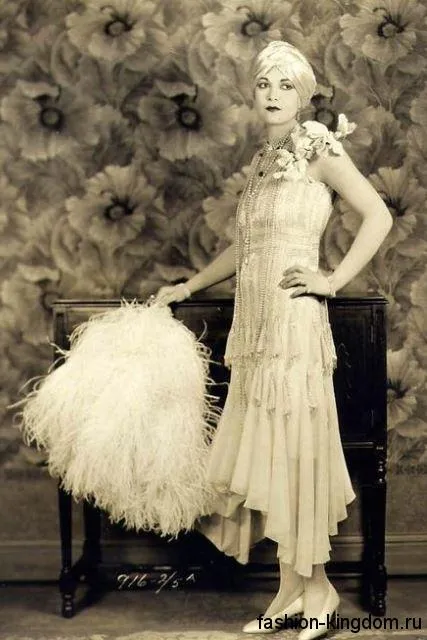 Длинное платье 1920 годов прямого силуэта, с драпировкой сочетается с жемчужными украшениями и туфлями на каблуке.