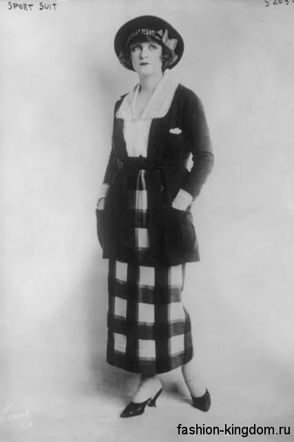 Длинная юбка в клетку 1920 годов прямого кроя в сочетании с белой блузой и длинным темным кардиганом.