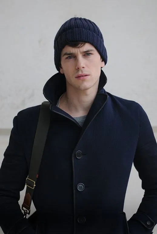 мужчина в черном пальто и синей шапке